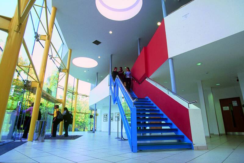 Blue steps in large modern atrium with a wall of windows on the left.